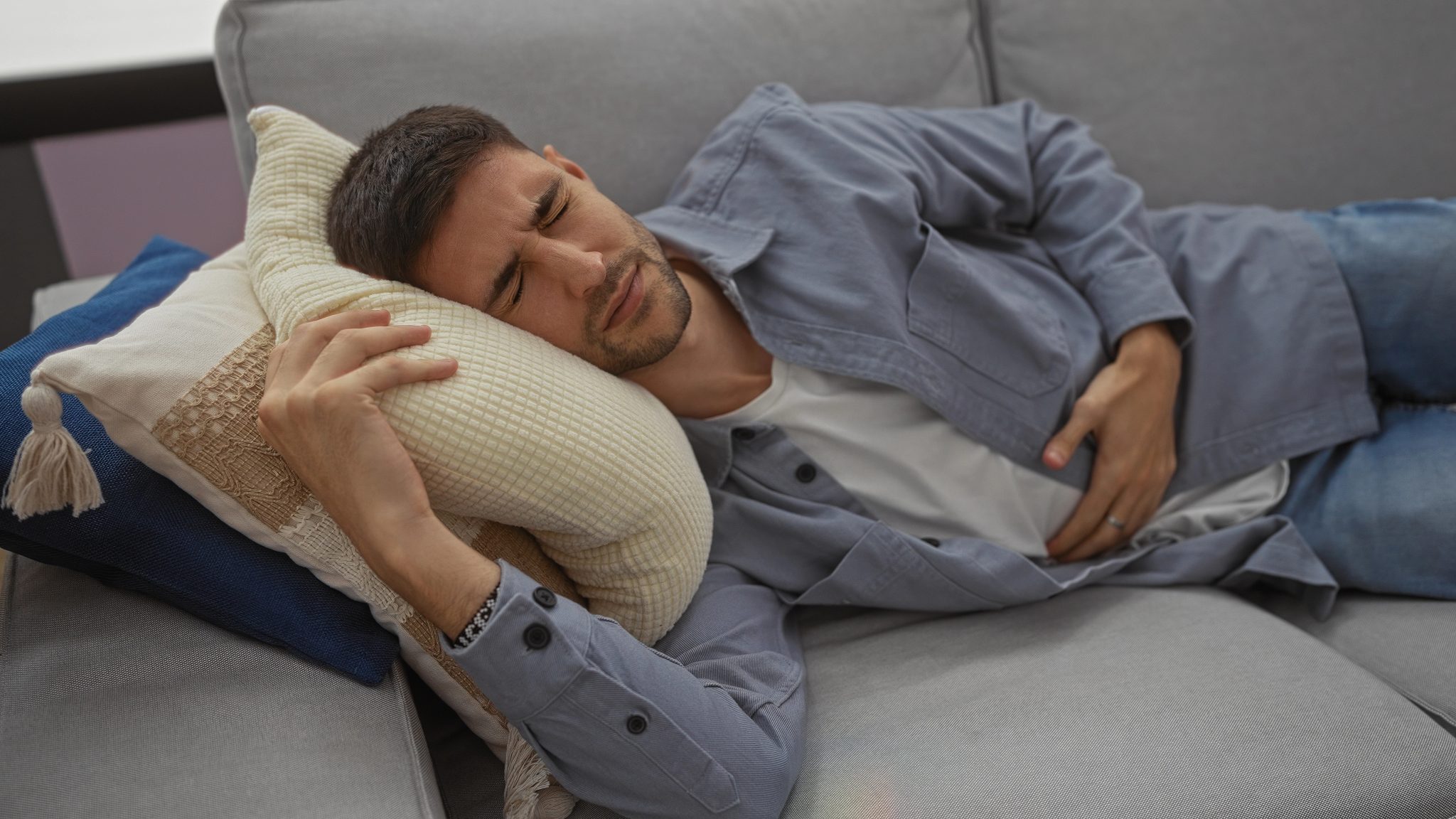 Man resting on a sofa with eyes closed, cuddling a cream textured pillow while leaning head on it. proving internal injuries personal injury sartell MN | Gabrielson Law Offices, LTD proving internal injuries personal injury sartell MN | Gabrielson Law Offices, LTD